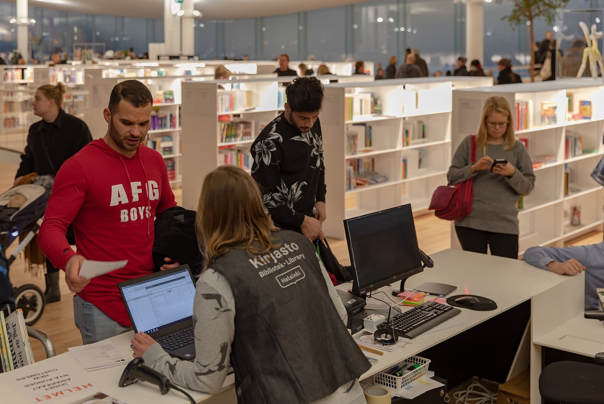Readers working at long tables in a modern library