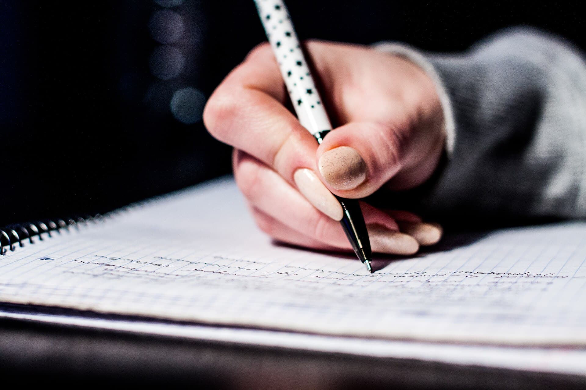 A hand writing notes with a pen in a notebook