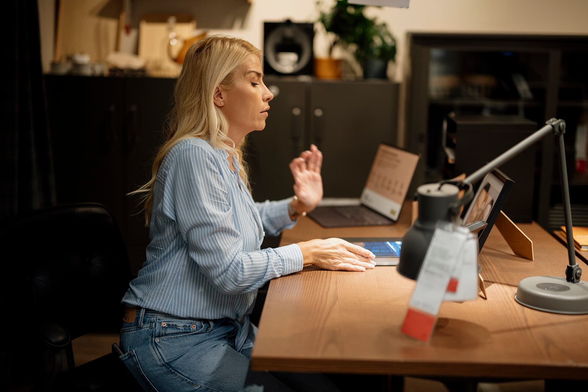 A woman working at a laptop in a home office